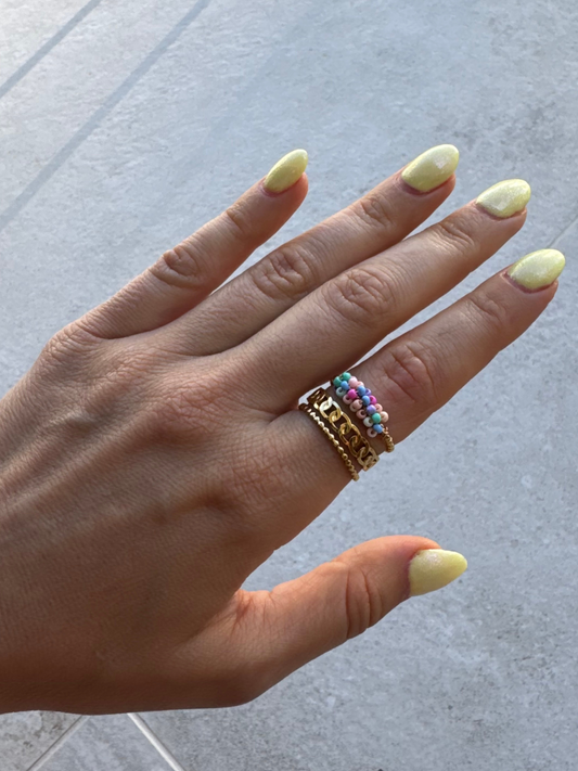 Anel dourado e missangas pequenas coloridas