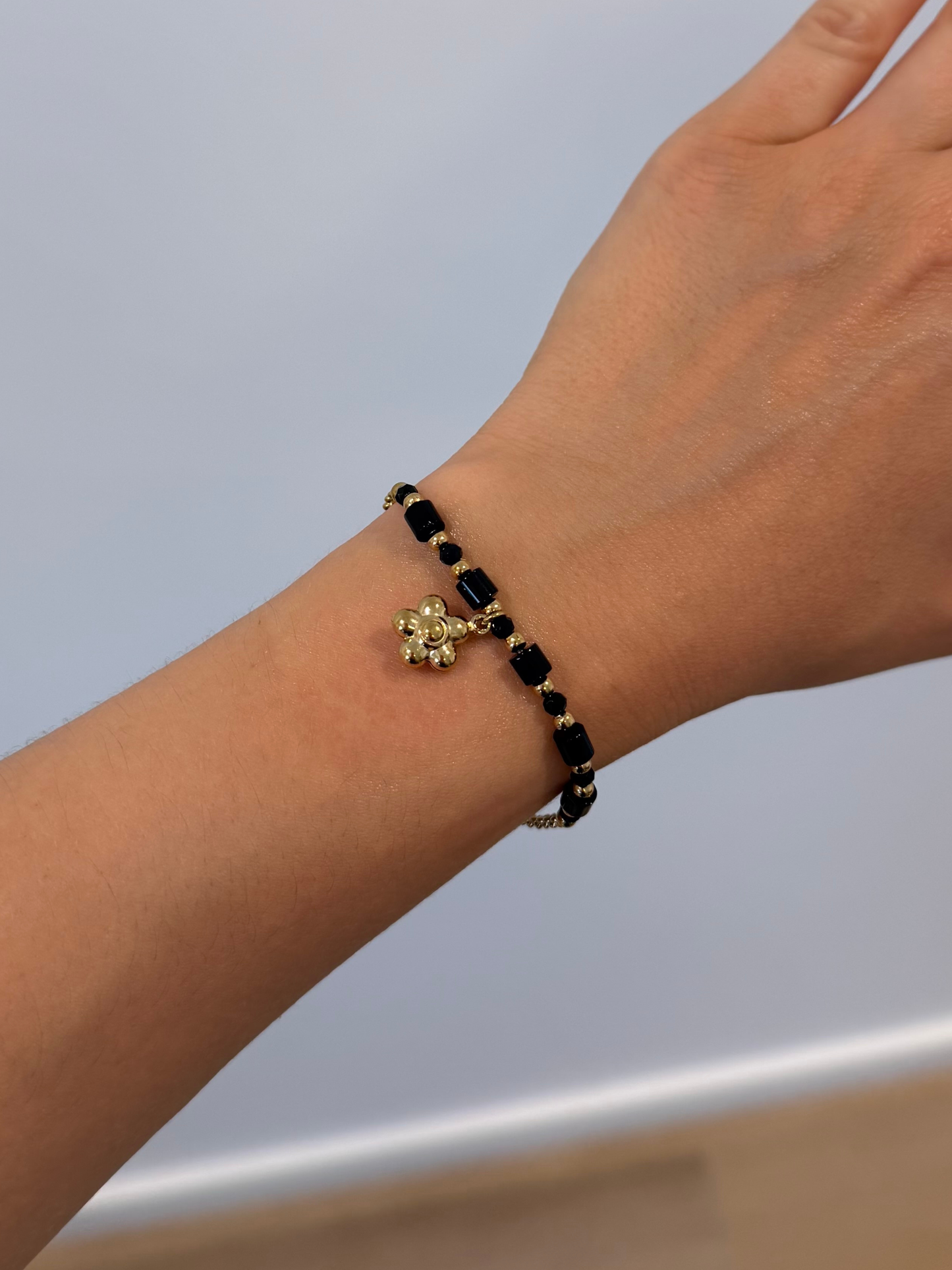 Pulseira preta com flor dourada
